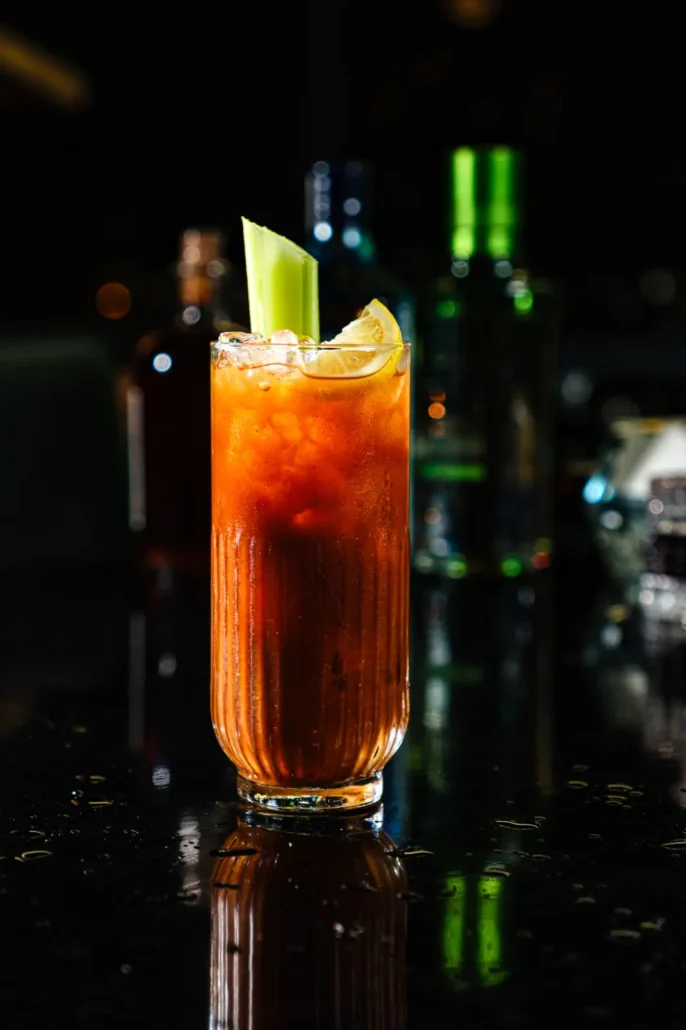 Ελκυστικό και λαχταριστό, ένα blody mary στο χώρο του bar φωτογράφιση ποτών και cocktail σε μπαρ, σύνθεση και styling σε dark background, ποτό σε πρώτο πλανο και θολό φόντο με μπουκάλια και πρώτες ύλες